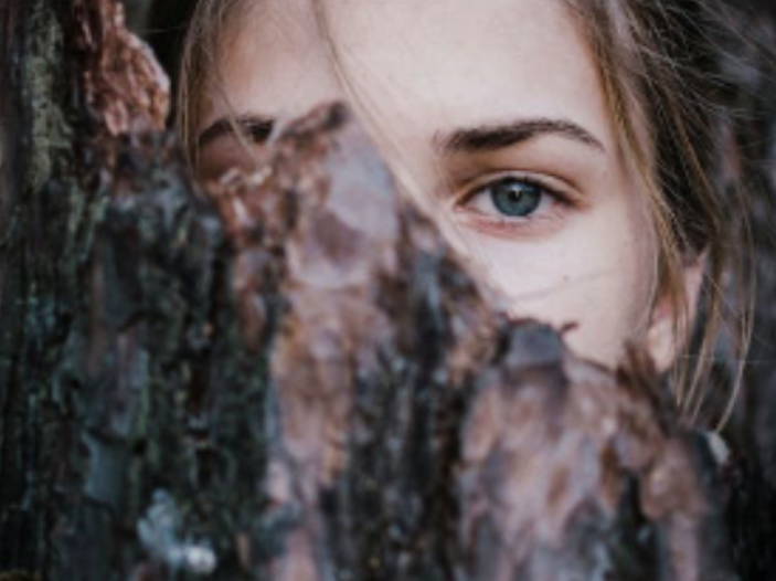 femme à moitié cachée derrière un tronc d'arbre - estime de soi