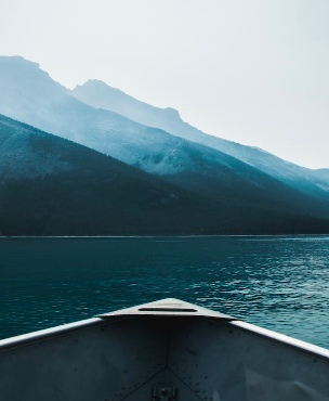 bateau seul au milieu de l'eau avec en arrière plan des montagnes